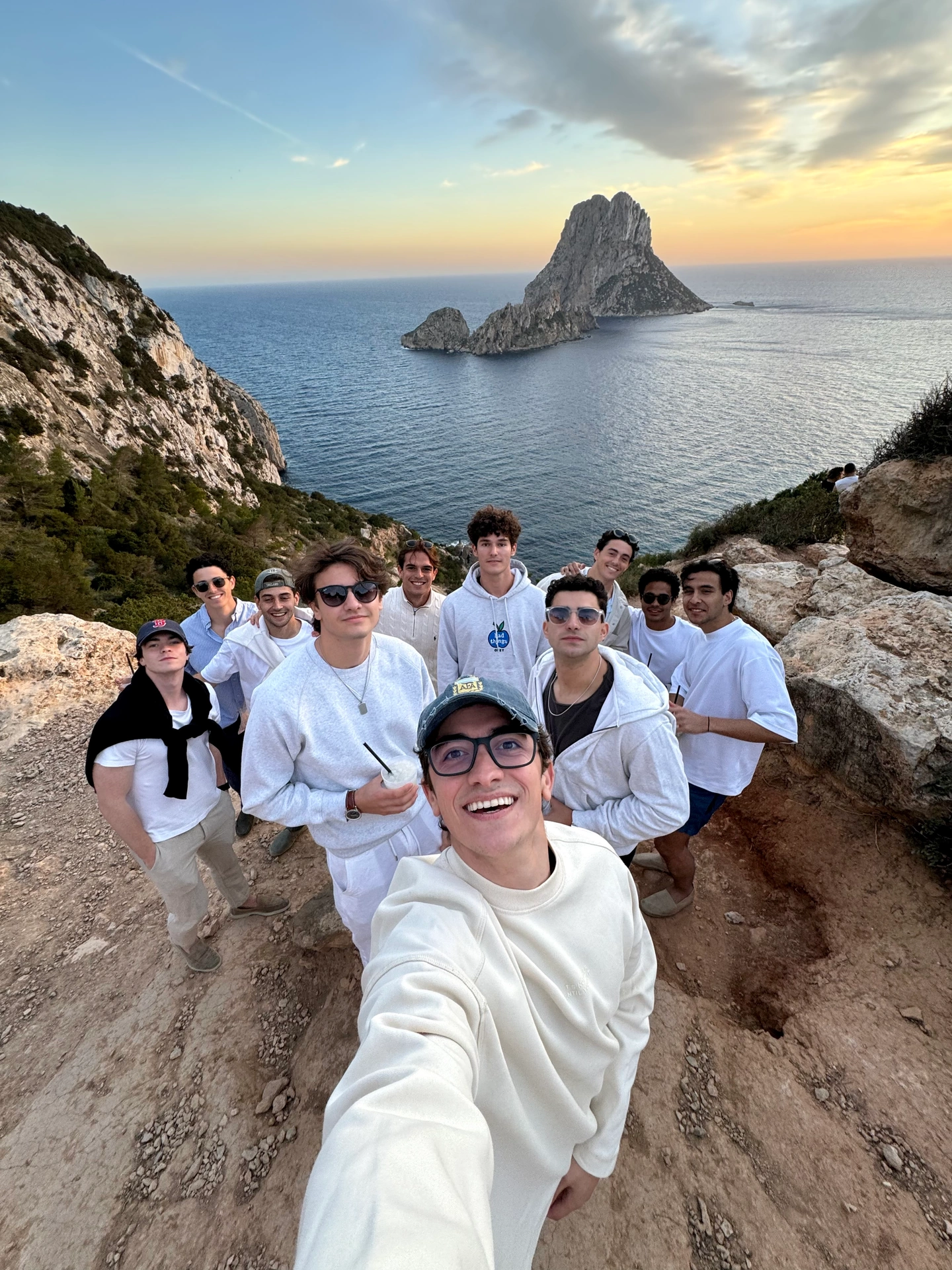 Group selfie with friends above Es Vedrà, Ibiza, at sunset